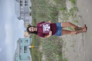 Emily with Aggies Sign on Galveston Beach