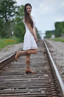 Young Brunette Model in White Dress & Cowgirl Boots on Railroad Tracks in Texas