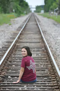 Brunette Teen Model Looking Back Sitting on Railroad Tracks