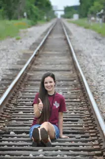 Emily Thumbs Up on Railroad Tracks in Texas