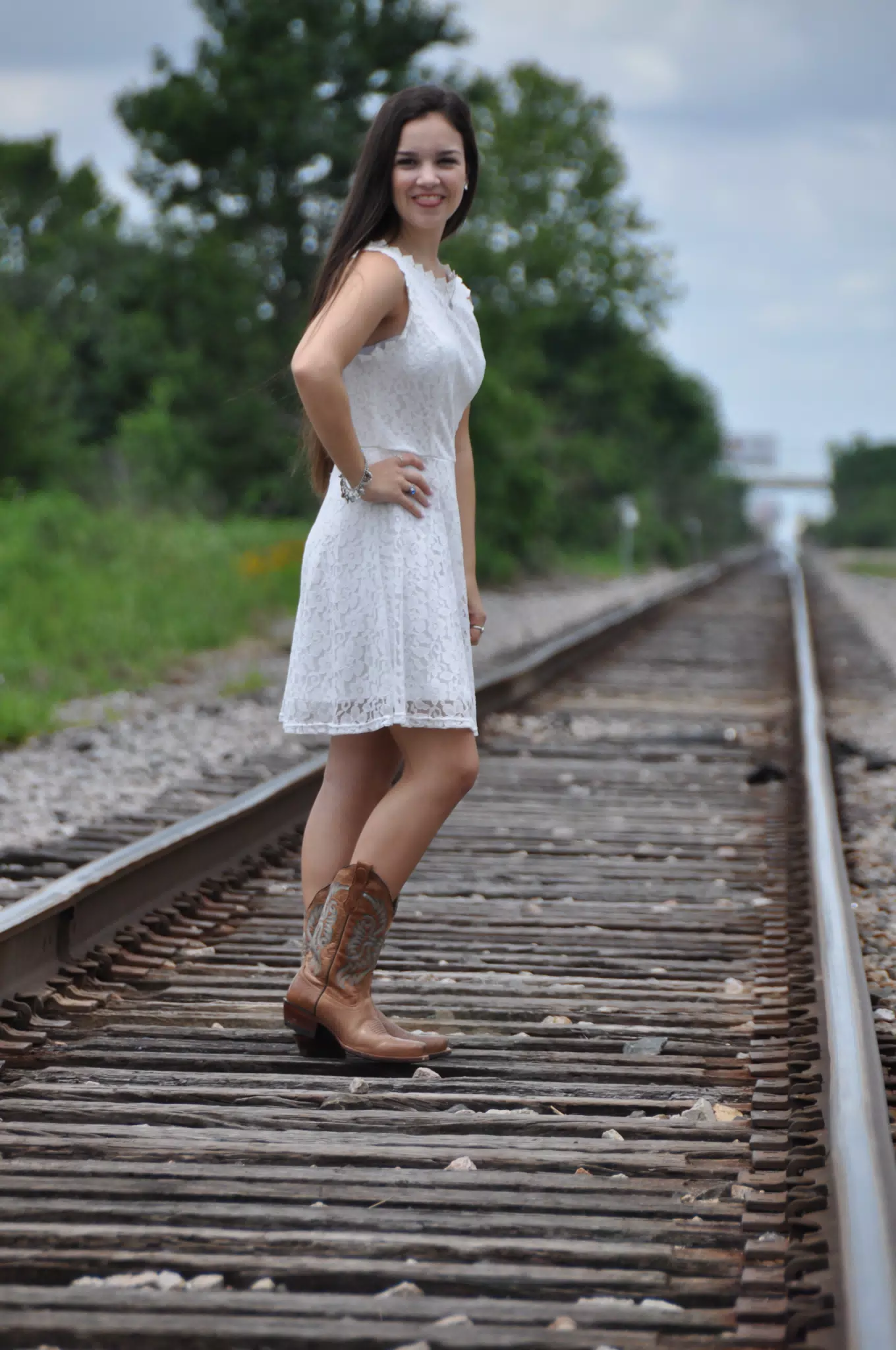 Emily Sticking Out Tongue in White Dress and Cowgirl Boots on Railroad Tracks