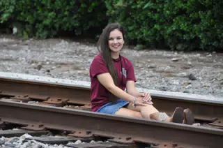Teen Model in Jean Mini Skirt Sitting on Railroad Tracks