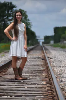Bright Sun on Girl in White Dress and Cowboy Boots on Train Tracks