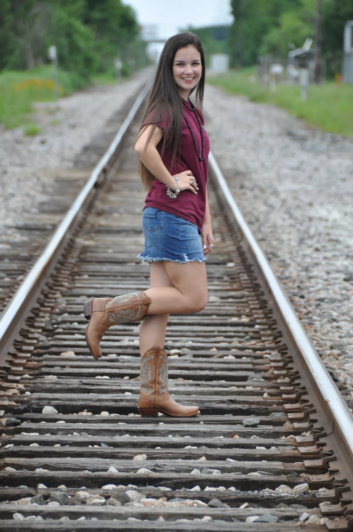 Model in Cowboy Boots on One Foot on Train Tracks