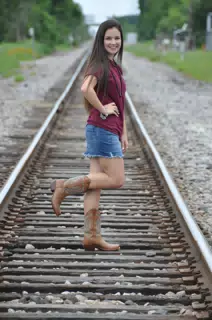 Model in Cowboy Boots on One Foot on Train Tracks