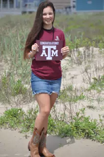 Emily Holding Aggie Sign on Galveston Beach