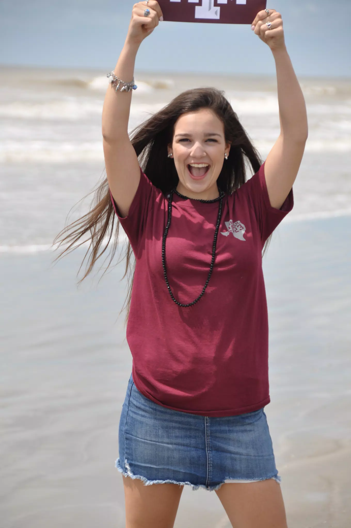 Girl Holding Up Aggie Sign on Galveston Beach