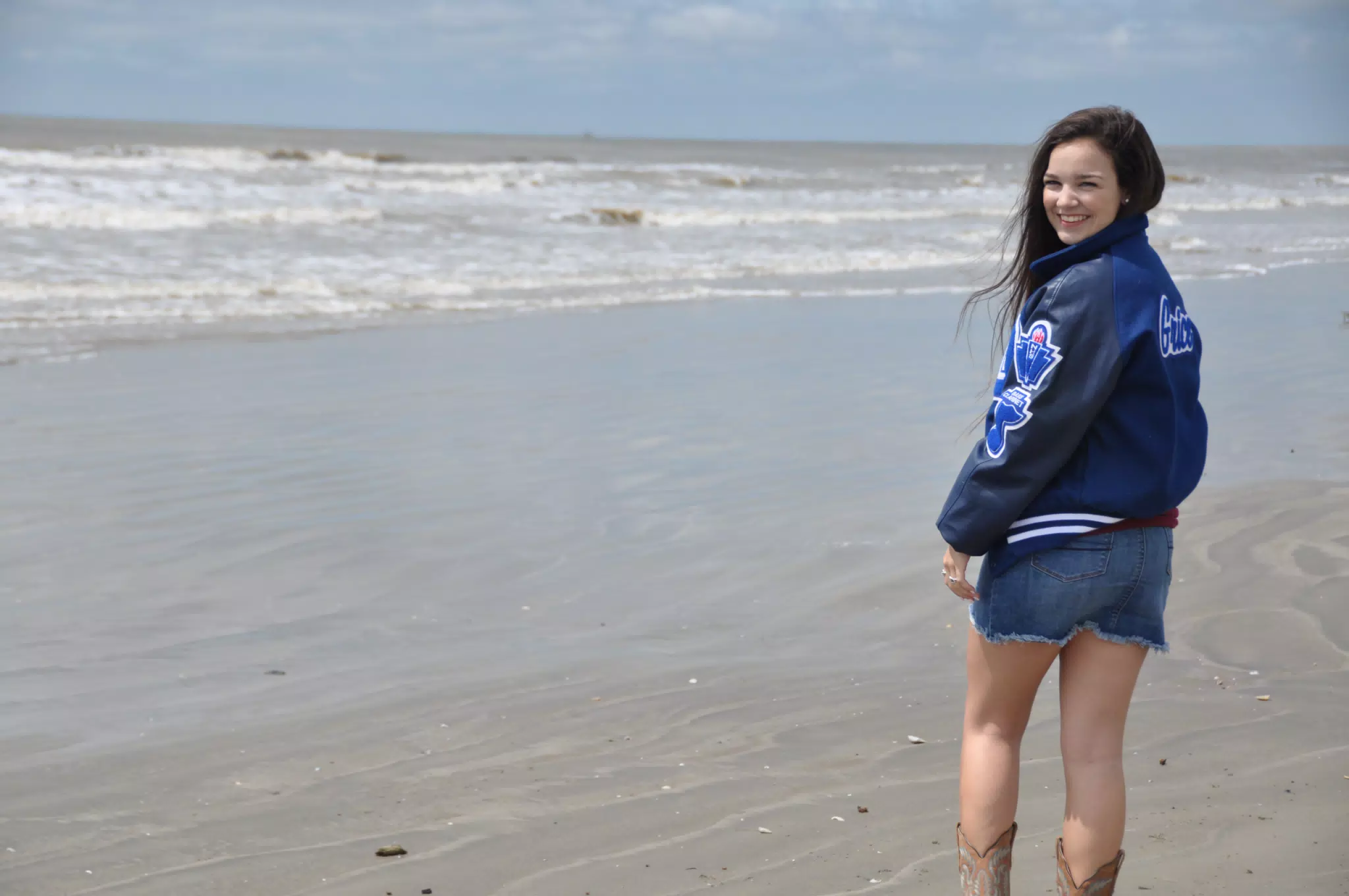 Girl in Letterman Over the Shoulder in Skirt and Boots on Galveston Beach