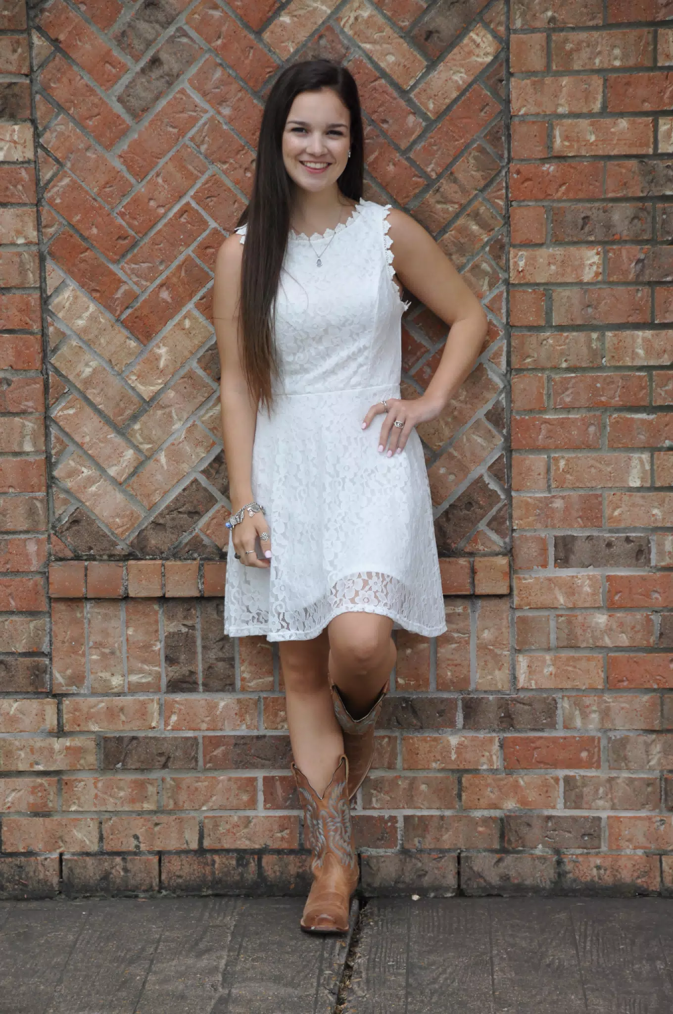 Girl in White Dress Leaning Casually on Brick Wall
