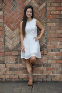 Girl in White Dress Leaning Casually on Brick Wall