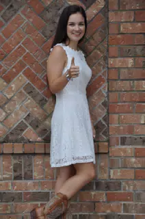 Model in White Dress by Brick Wall