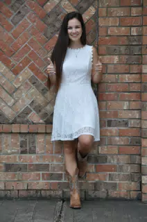Two Thumbs Up from Teen Model in White Dress and Cowboy Boots by Brick Wall