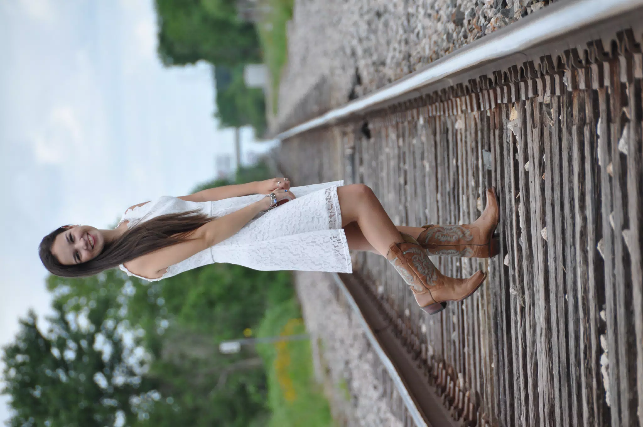 Model in White Dress and Cowboy Boots on Railroad Tracks