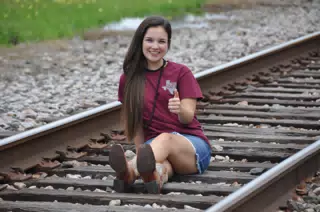 Brunette on Railroad Tracks in Jean Skirt Giving Thumbs Up