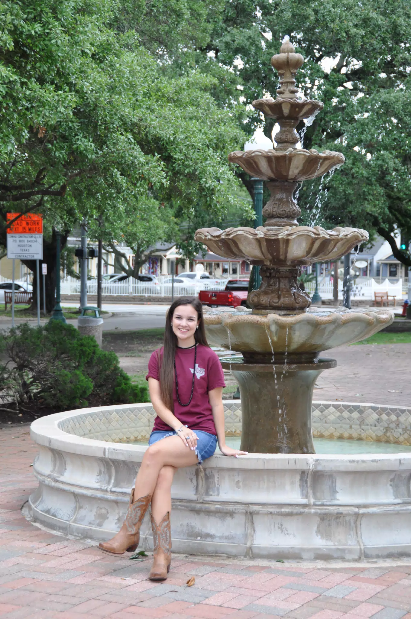 Brunette Teen Model Sitting on Fountain in Park in Galveston Texas in Denim Skirt and Cowboy Boots