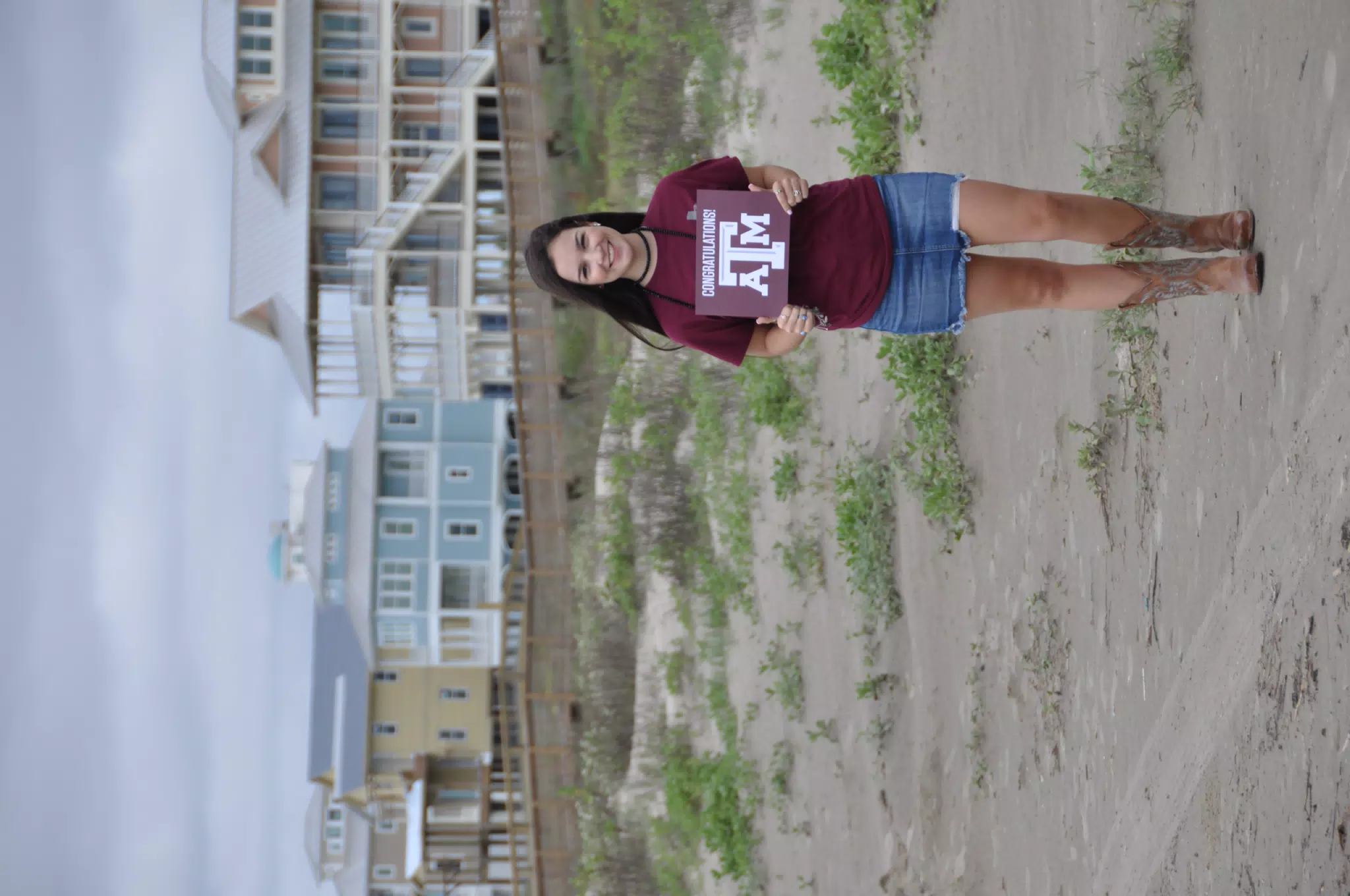 Brunette Teen Model in Jean Mini Skirt in Cowboy Boots on Galveston Beach in Texas with Aggies Sign
