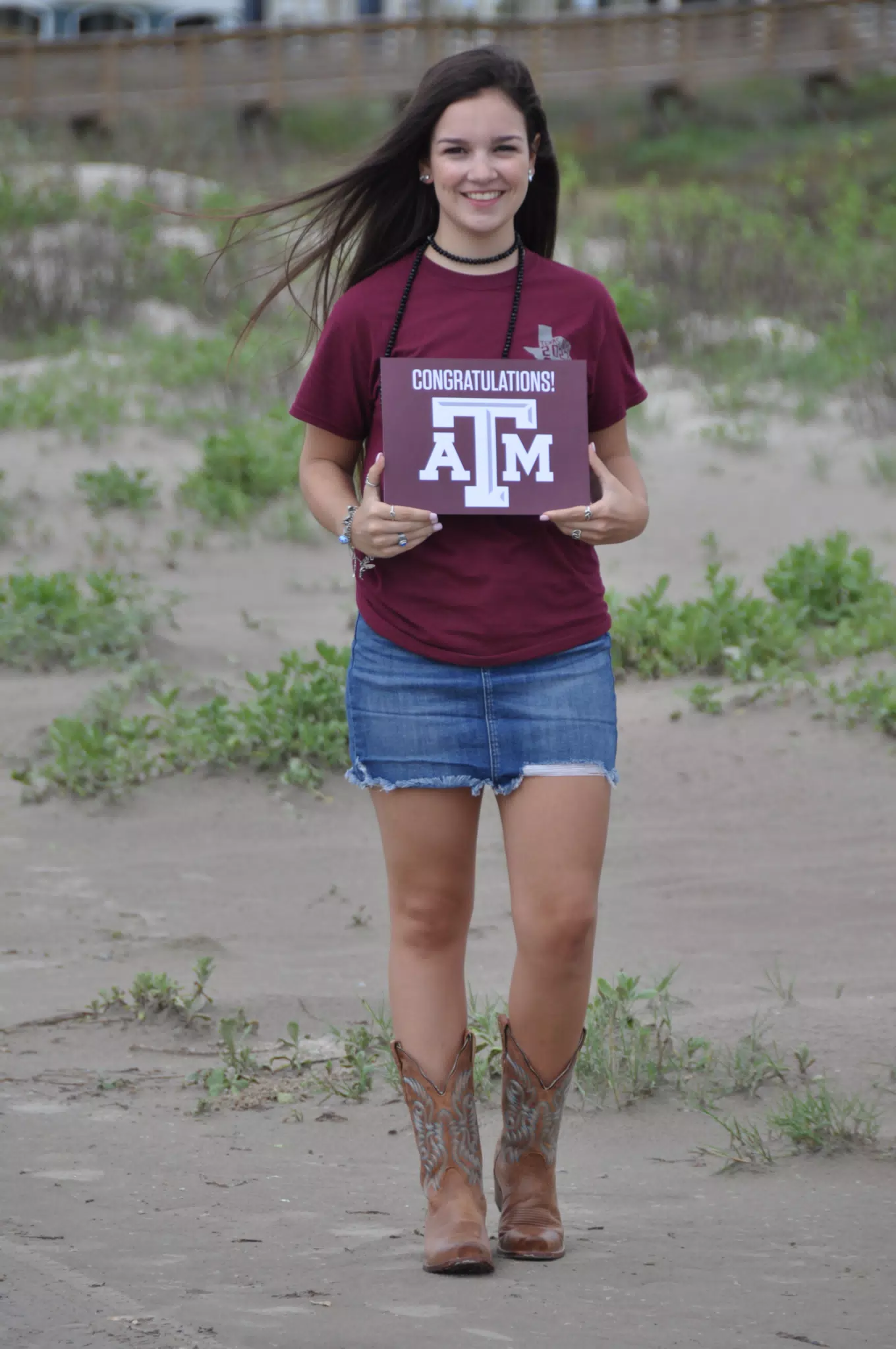 Emily Holding Aggies Sign in Cowboy Boots and Denim Skirt