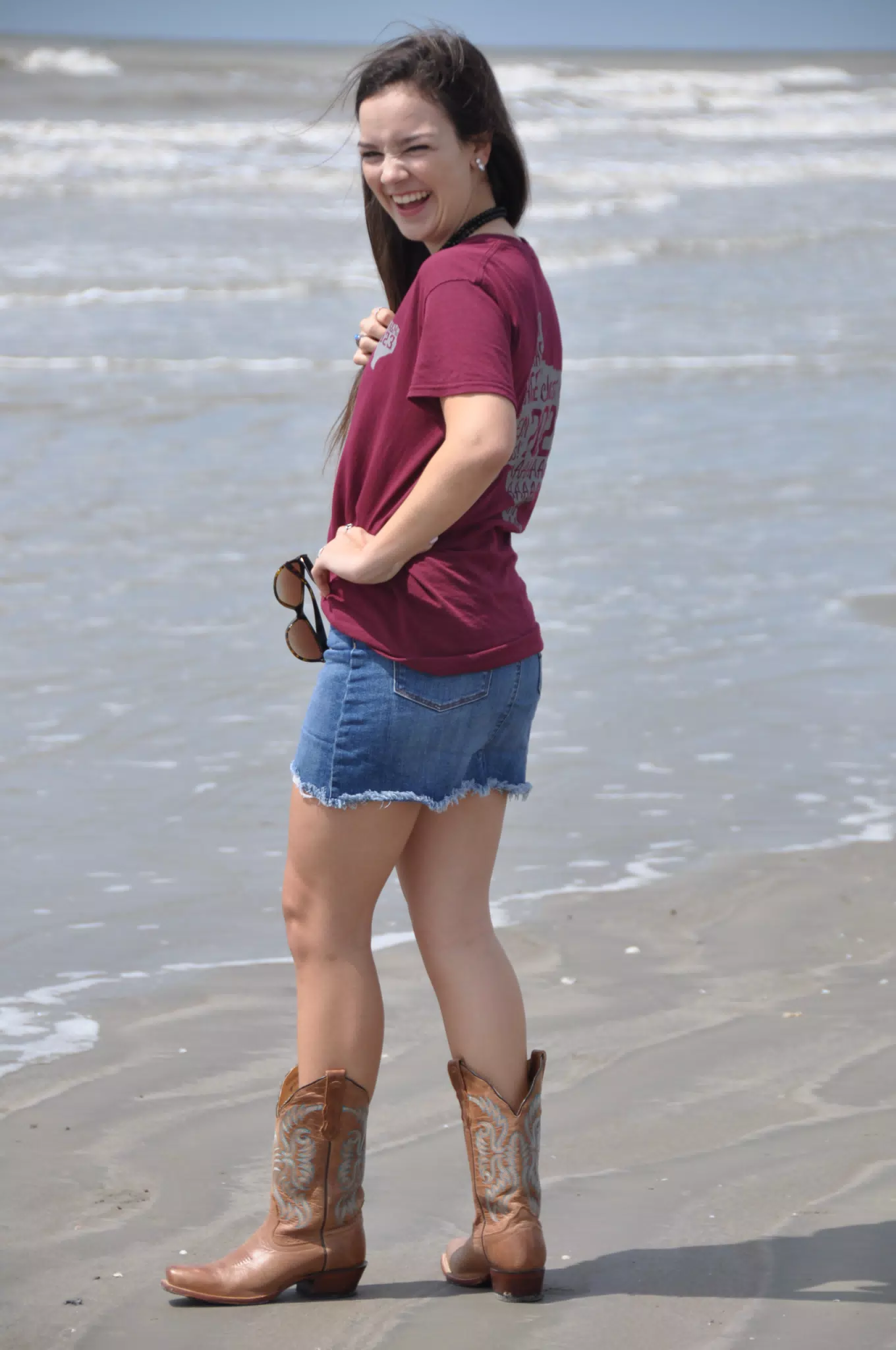 Brunette Teen Model in Boots and Miniskirt on Beach Laughing Over Her Shoulder