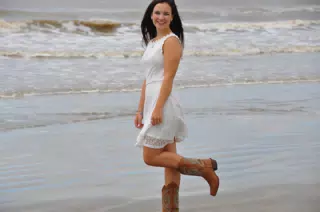 Teen Girl in White Dress Standing on One Foot on Galveston Beach in Cowboy Boots