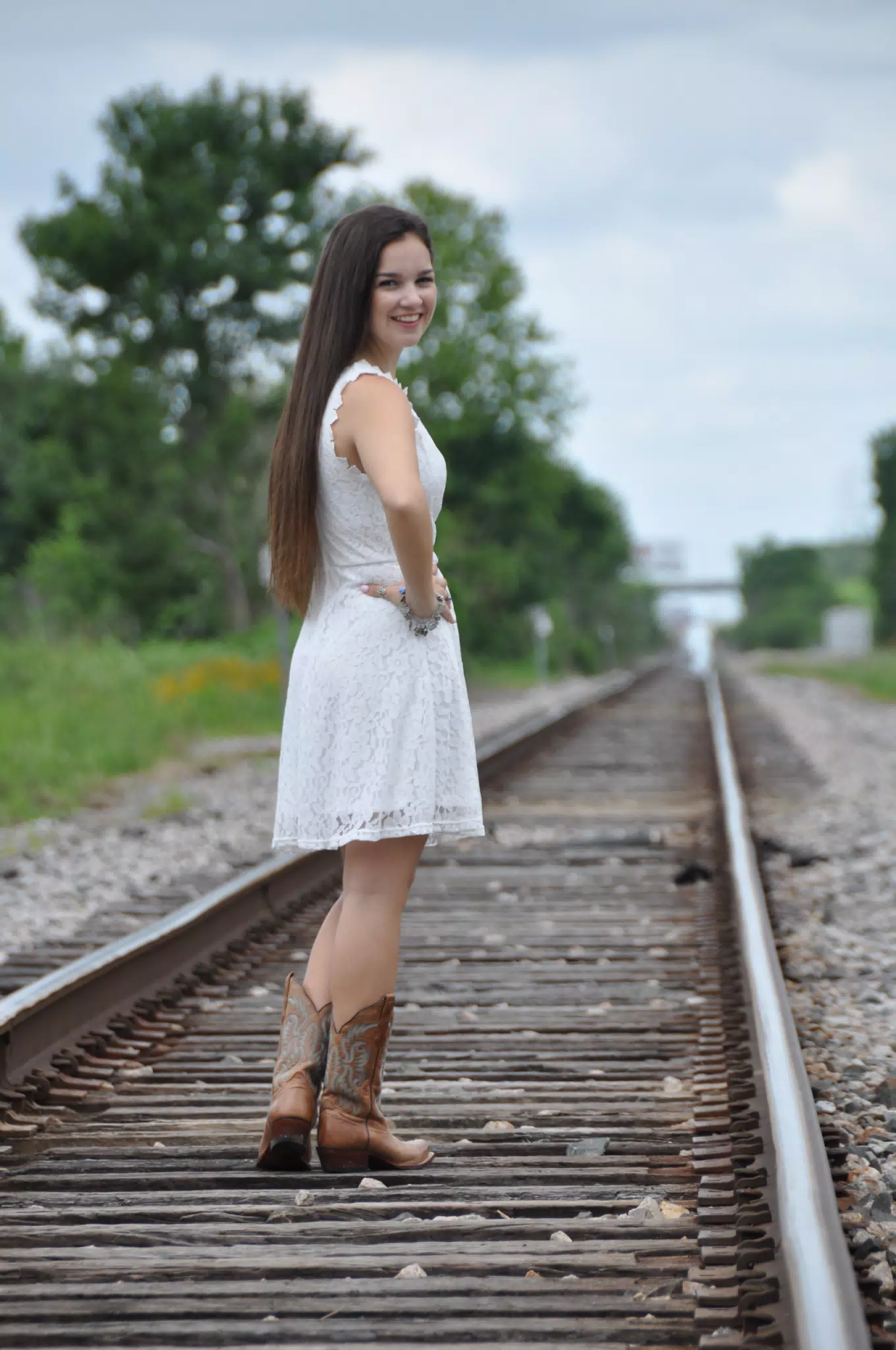 Model Looking Over Shoulder in White Dress on Railroad Tracks