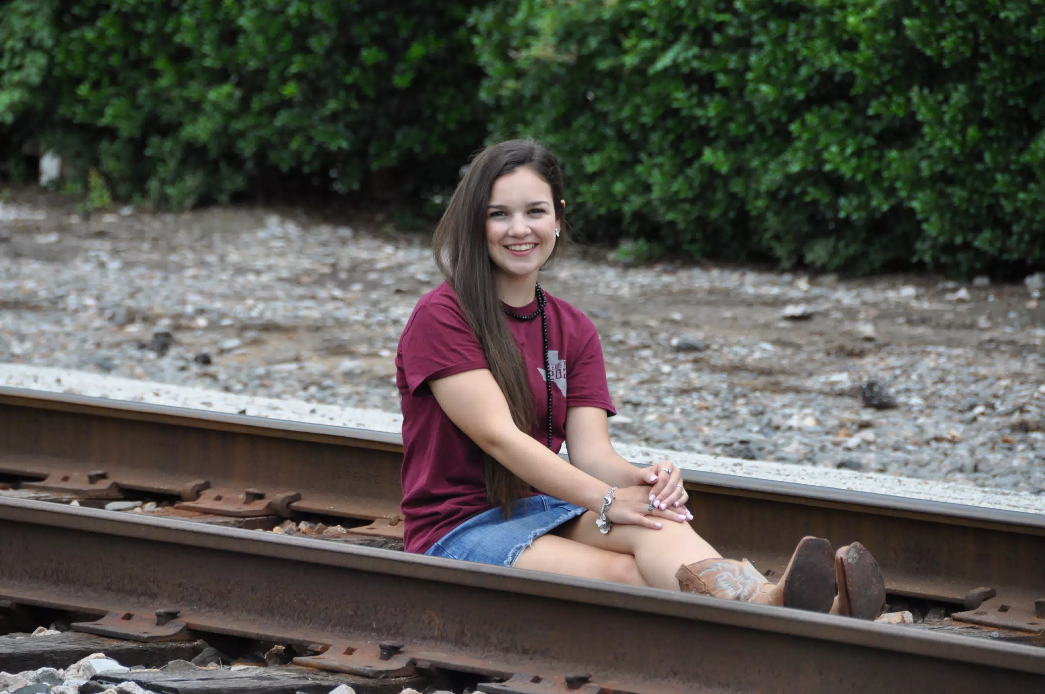 Brunette Teen Emily Sitting on Railroad Tracks in Texas in Denim Skirt and Cowboy Boots