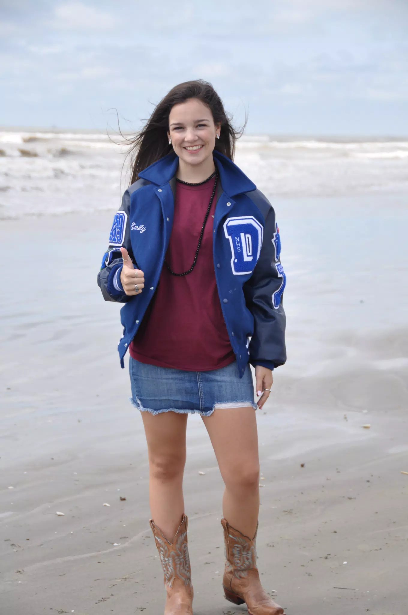 Teen Model Emily Thumbs Up in Letterman Jacket and Skirt on Beach