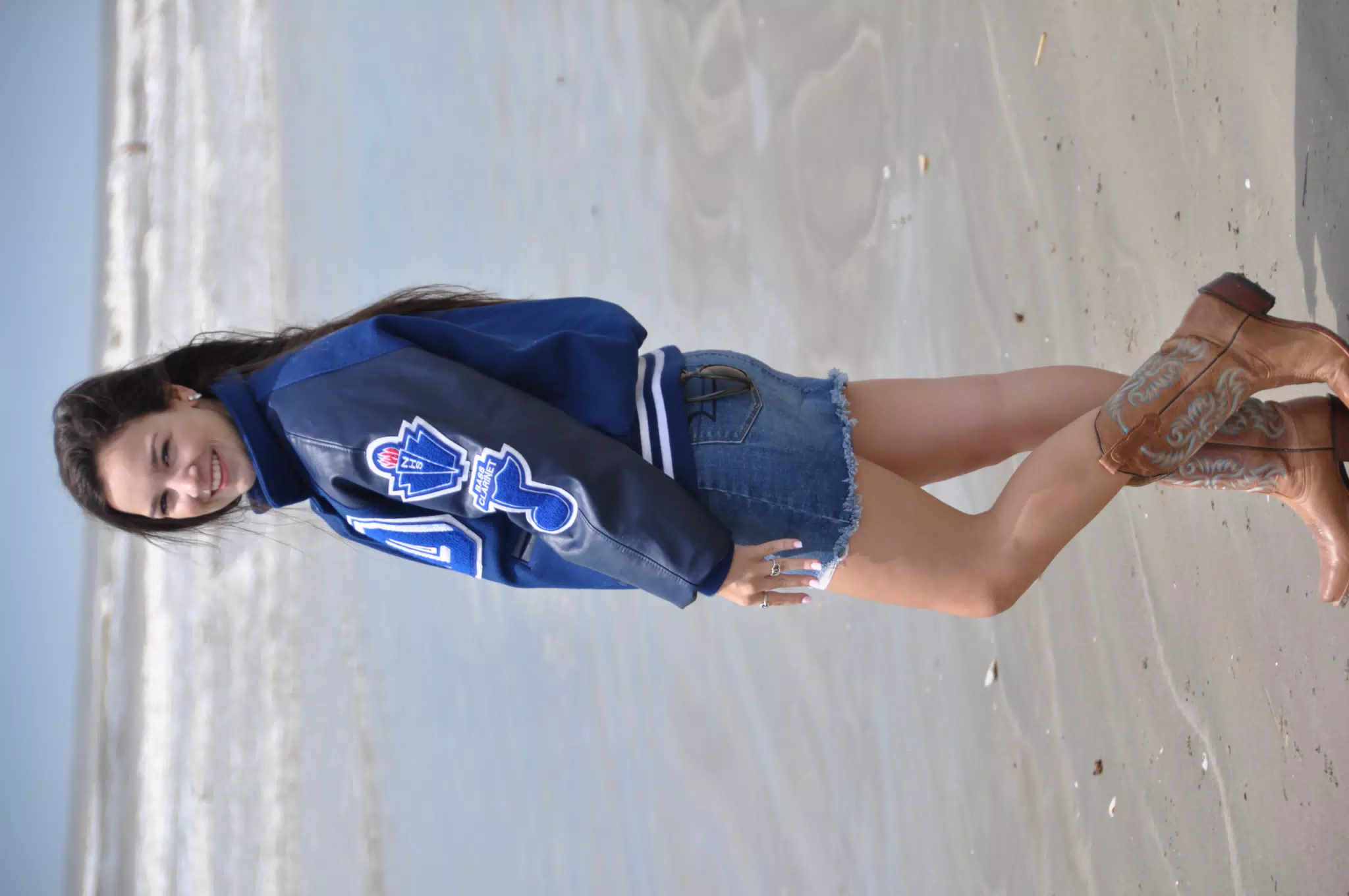 Model Looking Over Her Shoulder in Letterman Jacket and Cowgirl Boots on Galveston Beach