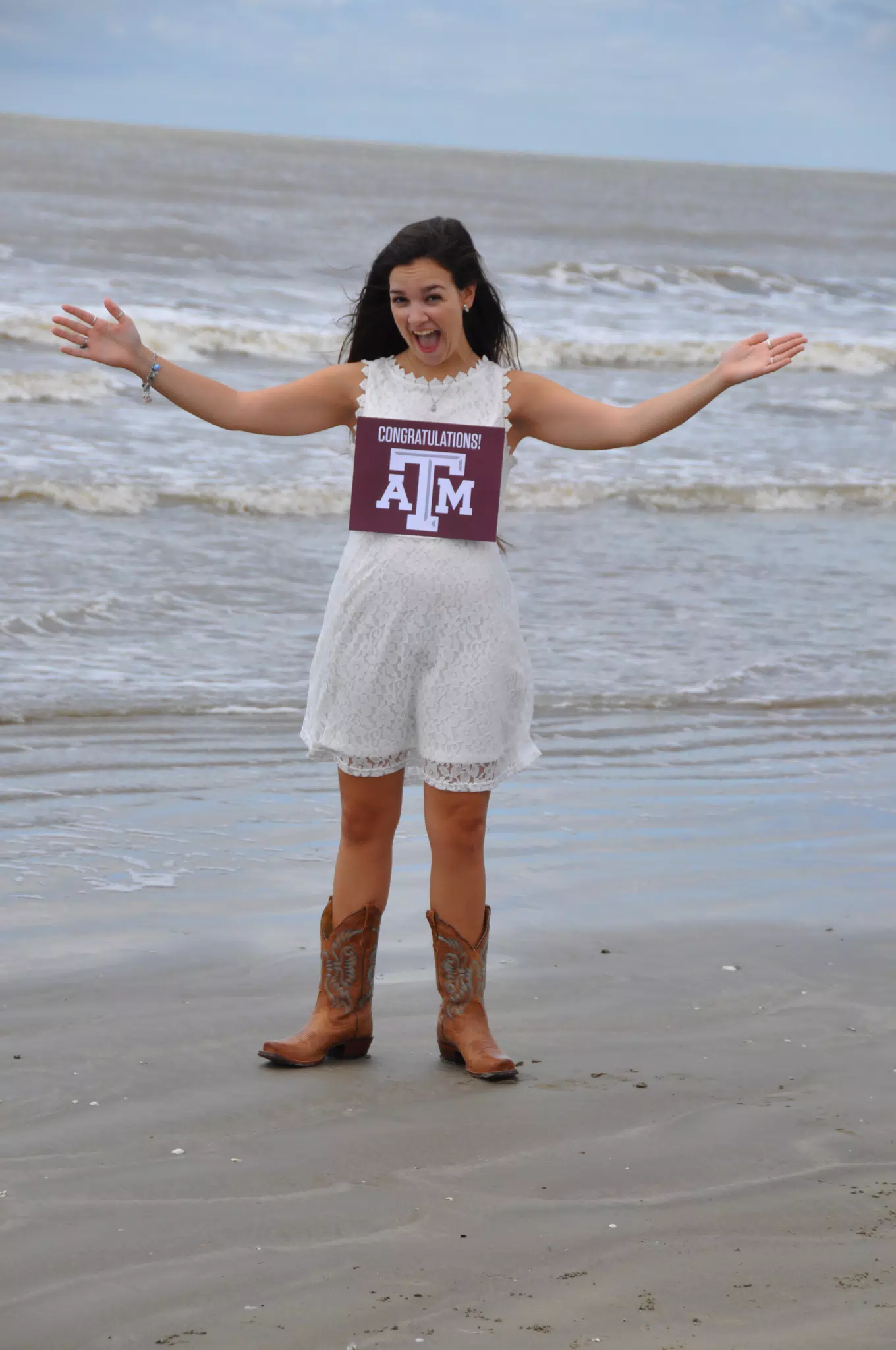 Emily with Aggies Sign in White Dress on Galveston Beach