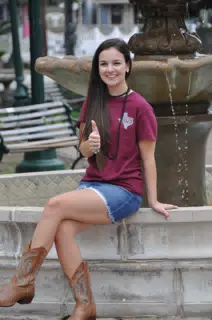 Emily Thumbs Up on Fountain in Skirt and Boots