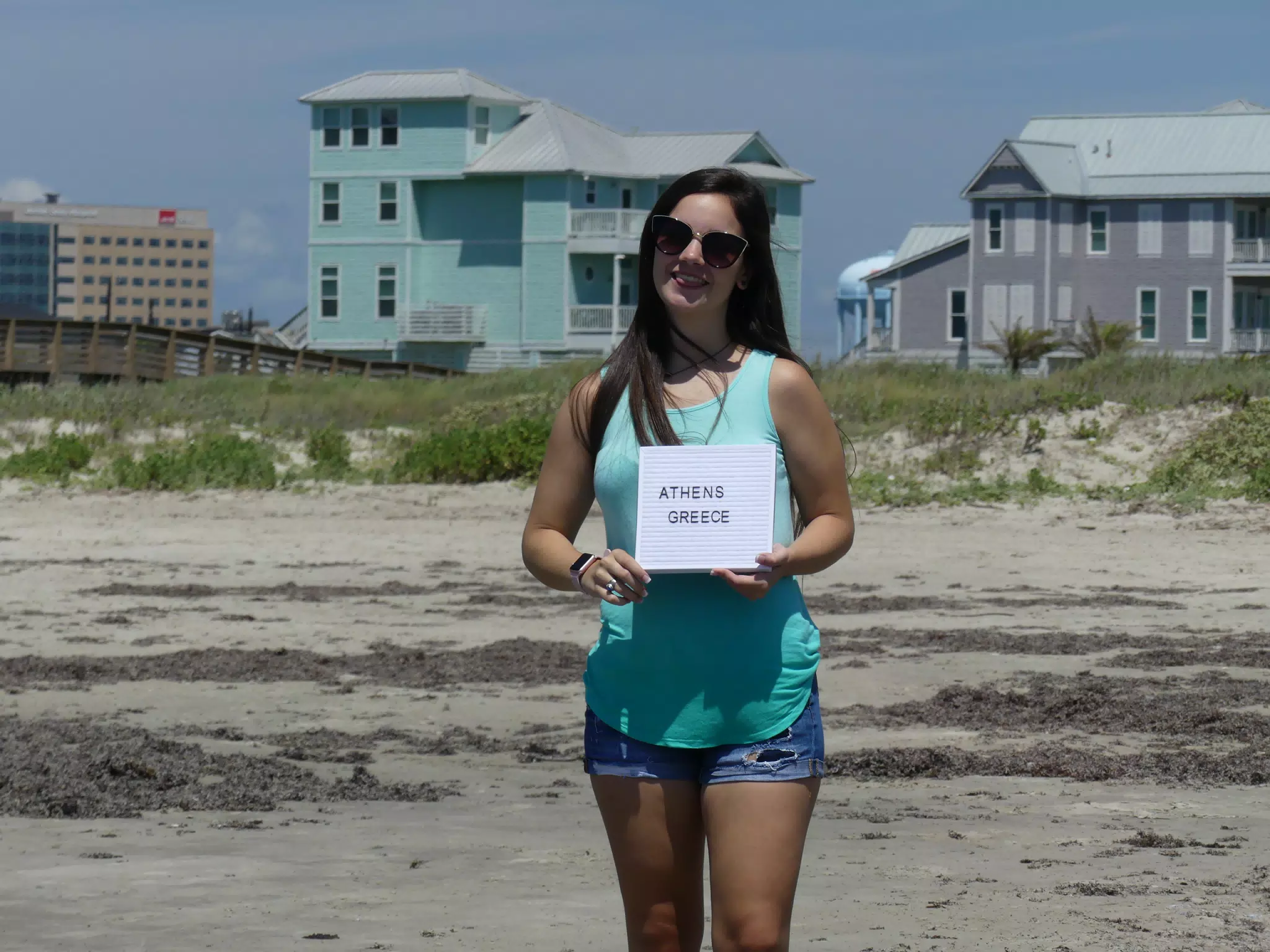 Emily Holding Sign on Galvetson Beach in Jean Shorts