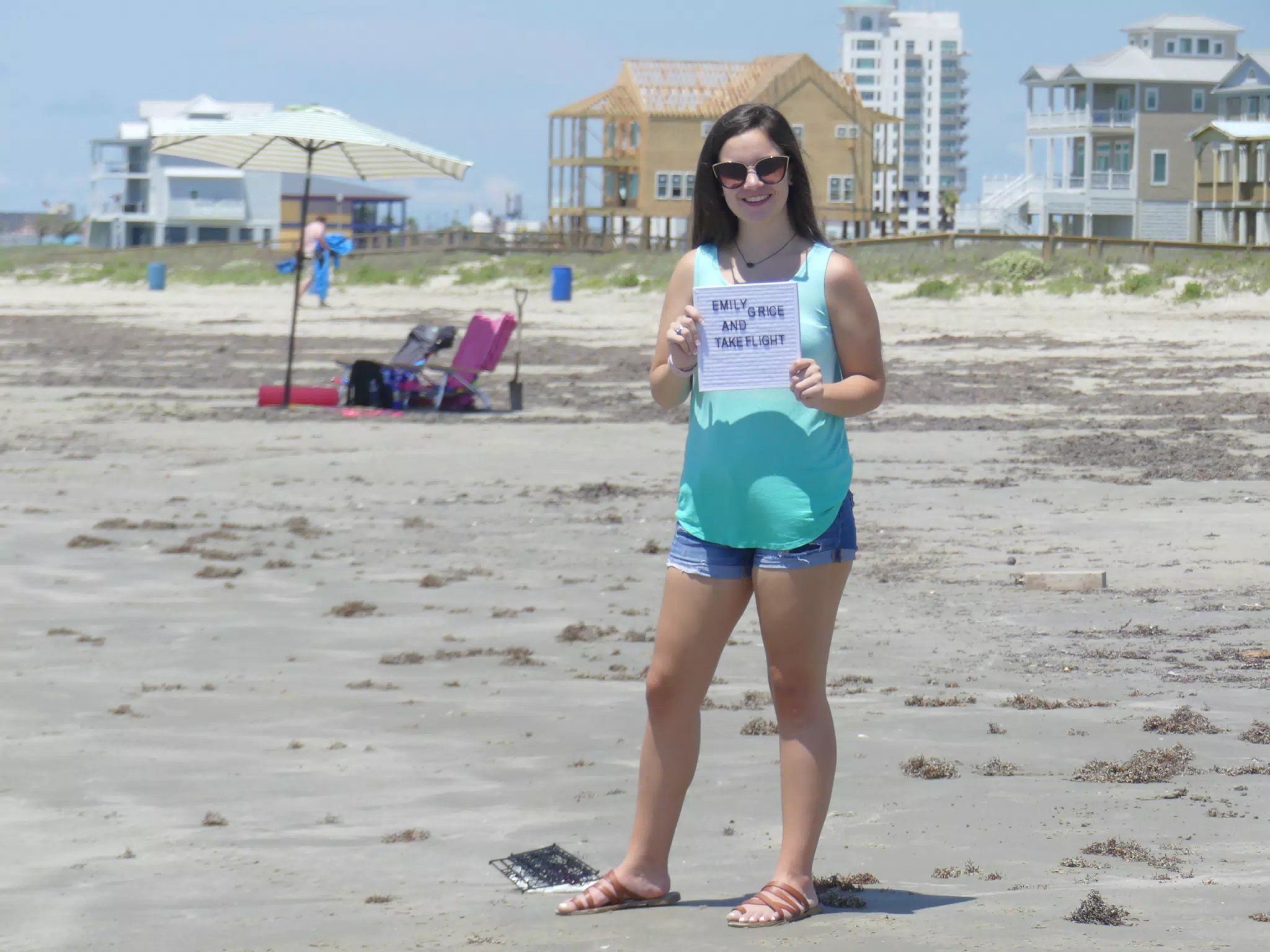Emily with Take Flight Sign on Galveston Beach