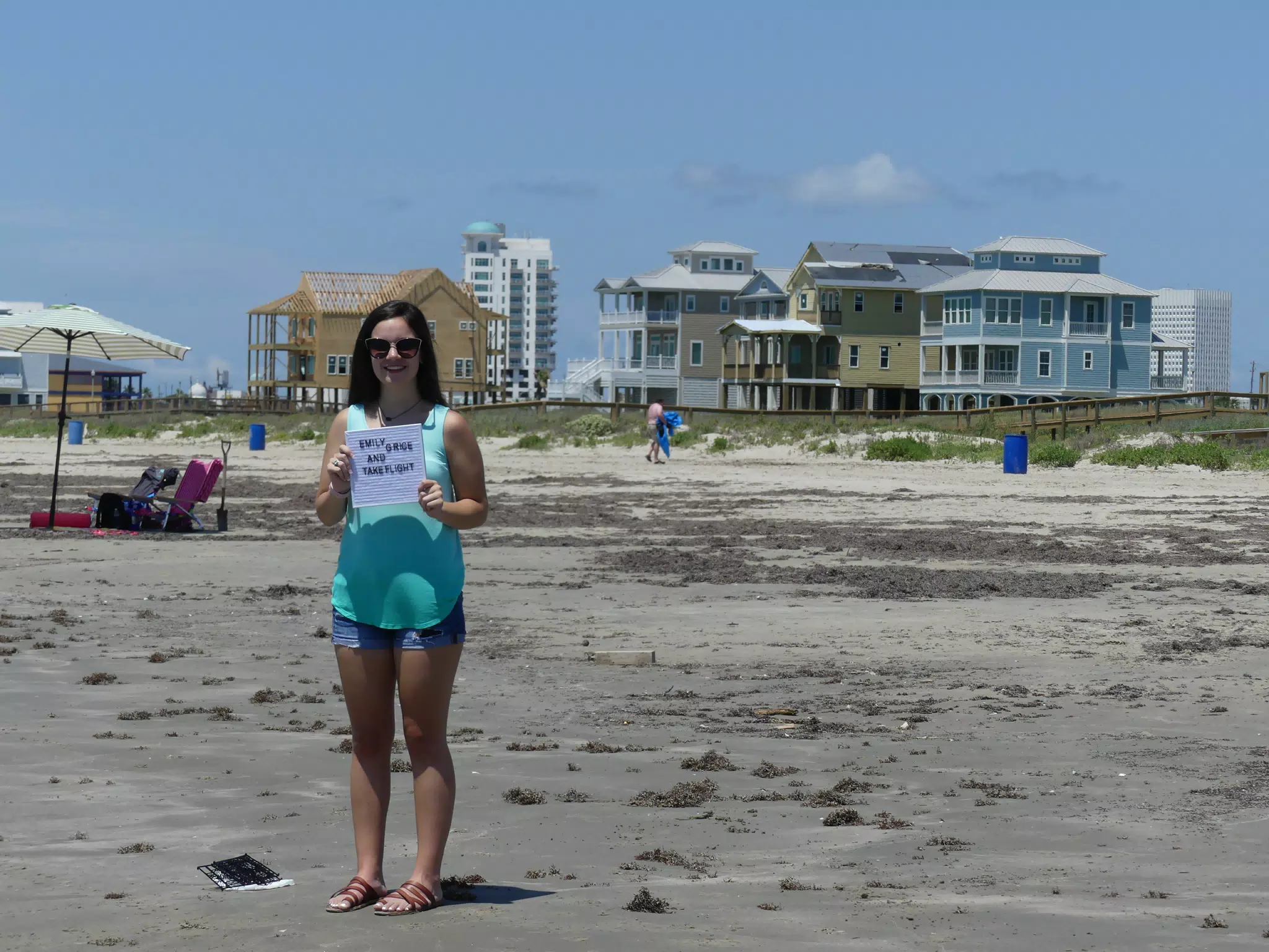 Emily with Take Flight Sign on Galveston Beach