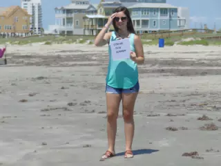 Emily with Coming This Summer Sign on Galveston Beach