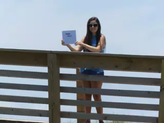 Emily Holding Sign on Galveston Beach Boardwalk