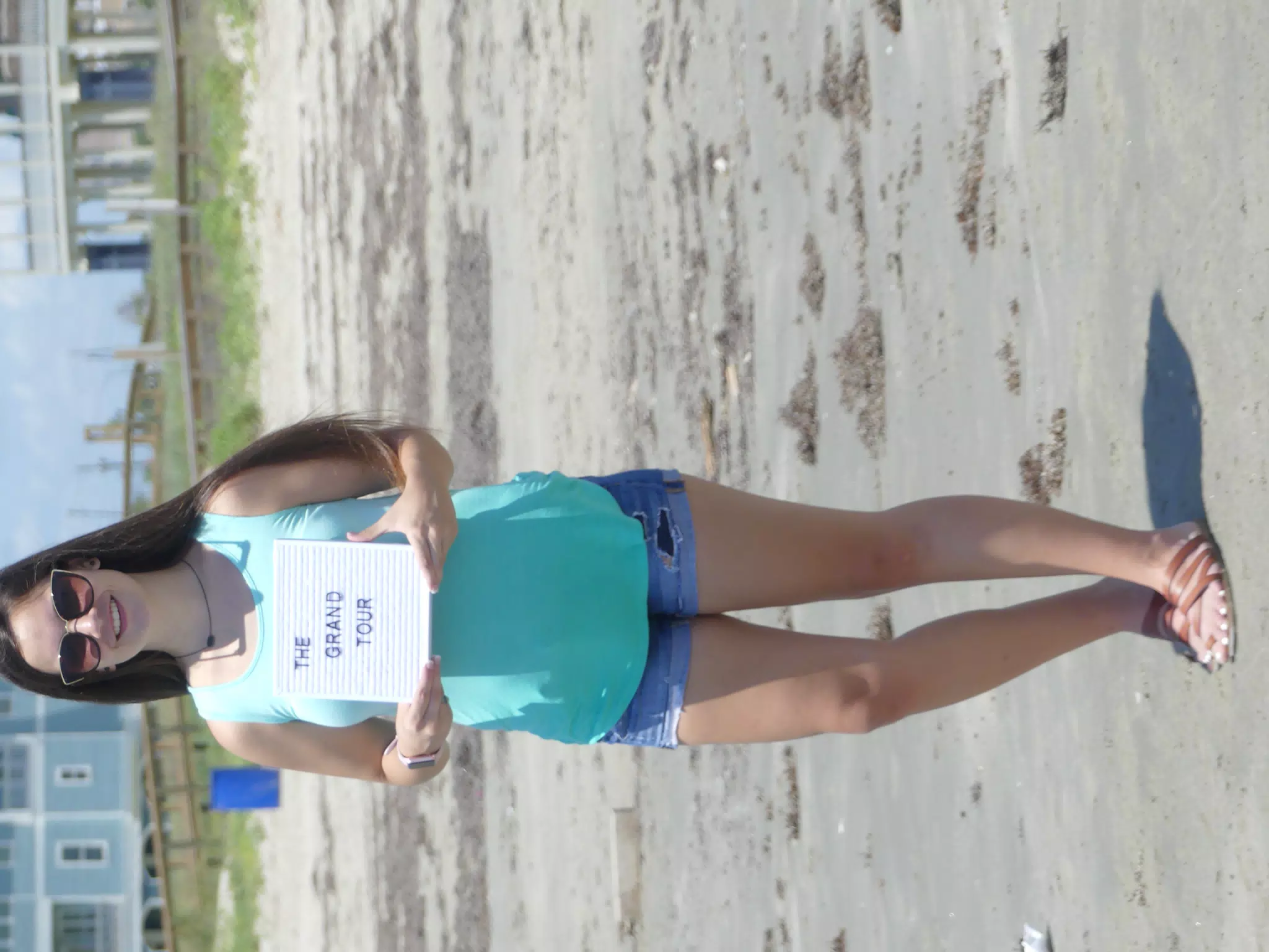 Grand Tour Sign on Galveston Beach with Emily in Denim Shorts