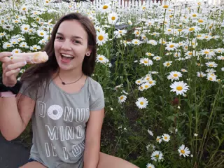 Girl Eating Donut in Field of Flowers