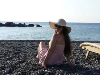 Girl Looking Back on Kamari Beach on Aegean Sea on Santorini