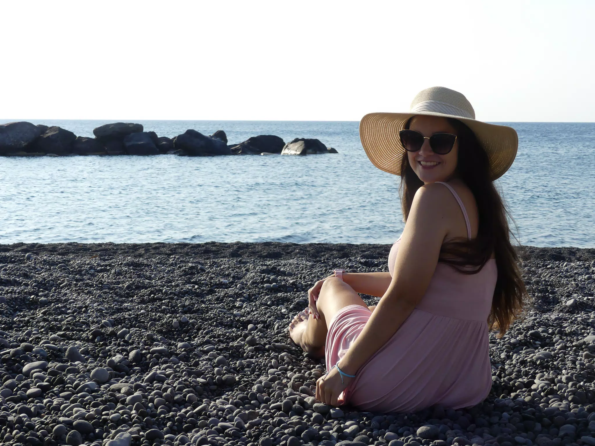 Girl Looking Back Sitting on Beach on Santorini