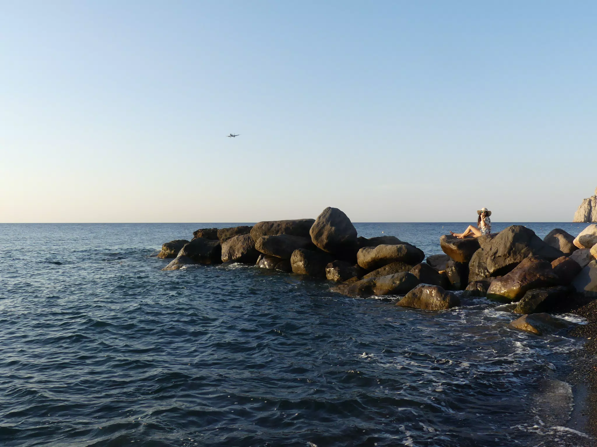 Airplane Landing on Santorini Over Girl Laying on Beach