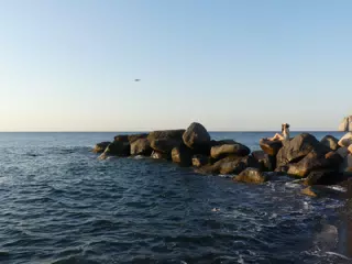 Airplane Landing on Santorini Over Girl Laying on Beach