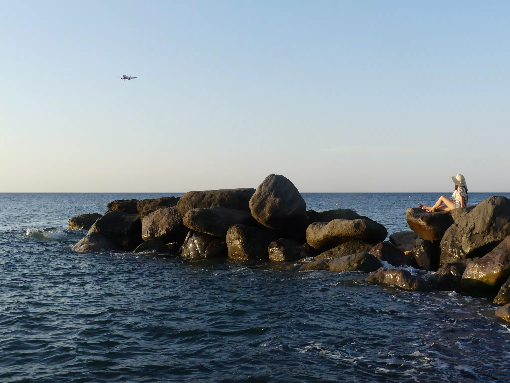 Girl Watching Airplane Land on Santorini from Beach at Sunrise