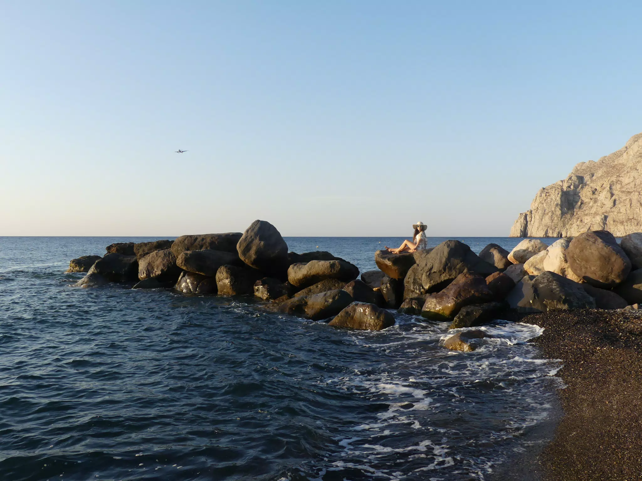 Airplane Landing over Girl on Beach at Kamari, Santorini