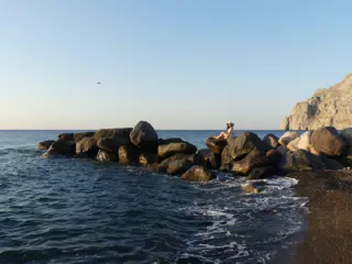 Airplane Landing over Girl on Beach at Kamari, Santorini