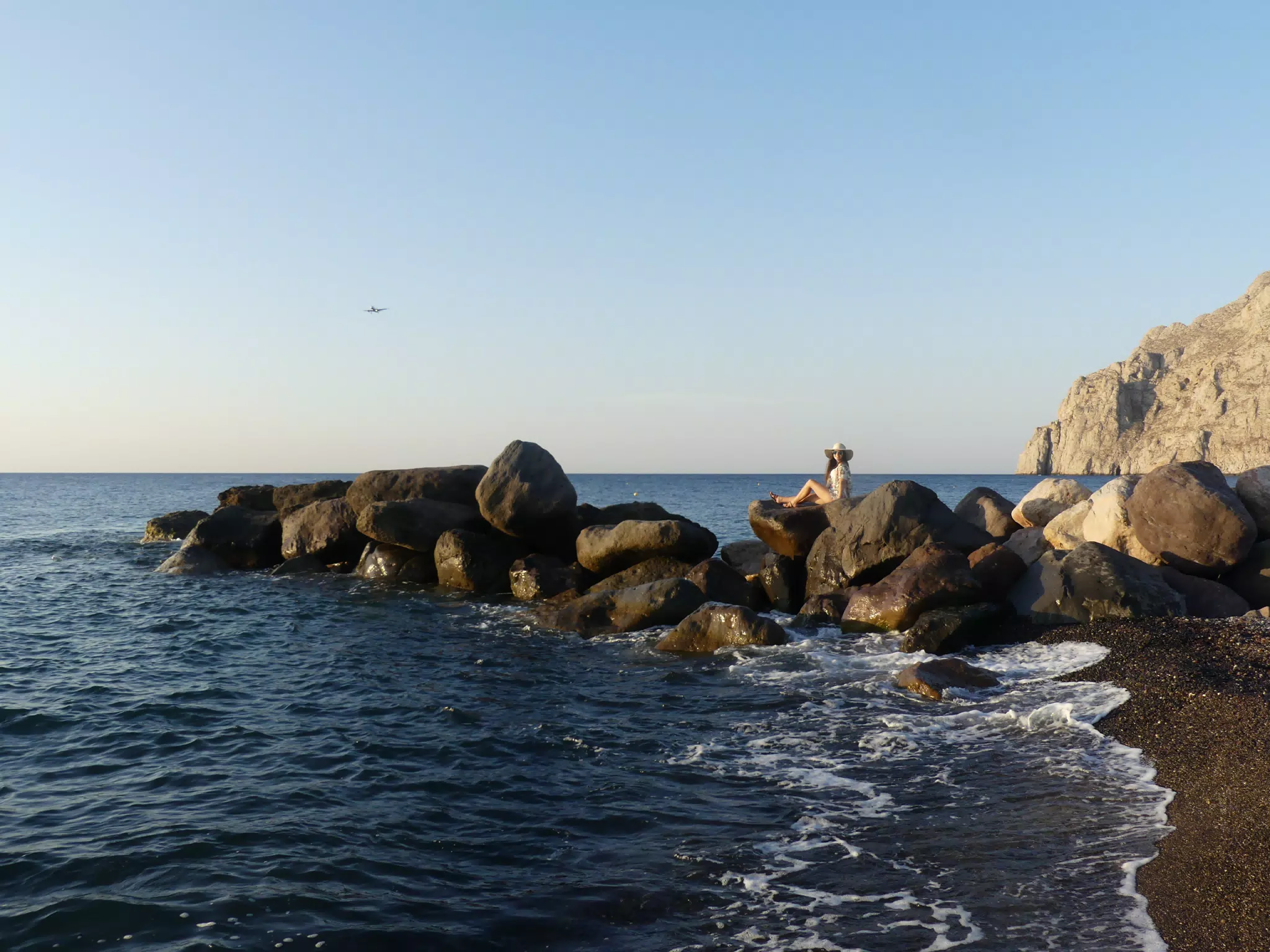 Girl on Rocks on Kamari Beach, Santorini on the Aegean Sea