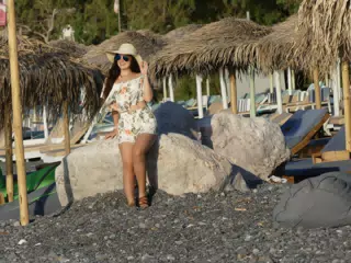Emily in Hat and Sunglasses on Kamari Beach on Santorini on Rock
