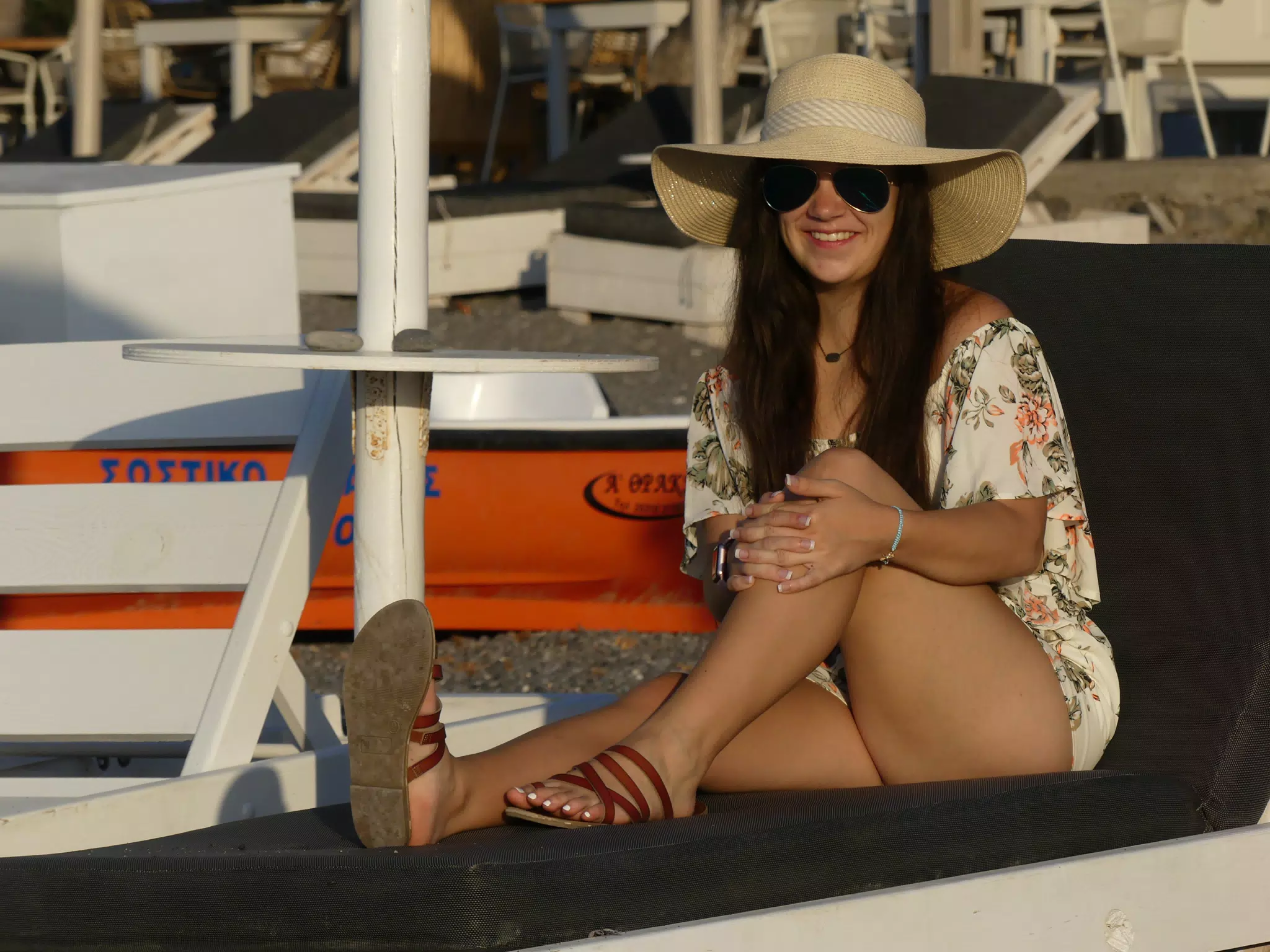 Emily on Lounge Chair on Santorini Beach in Hat and Sunglasses