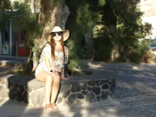 Girl in Hat Under Tree on Santorini