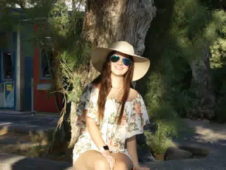 Girl Sitting on Curb Around Tree on Santorini