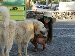 Girl in Hat with Dog on Street in Santorini