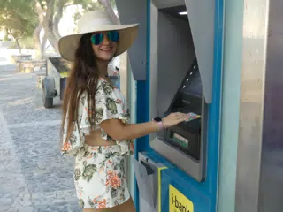 Teen Girl Using ATM on Santorini